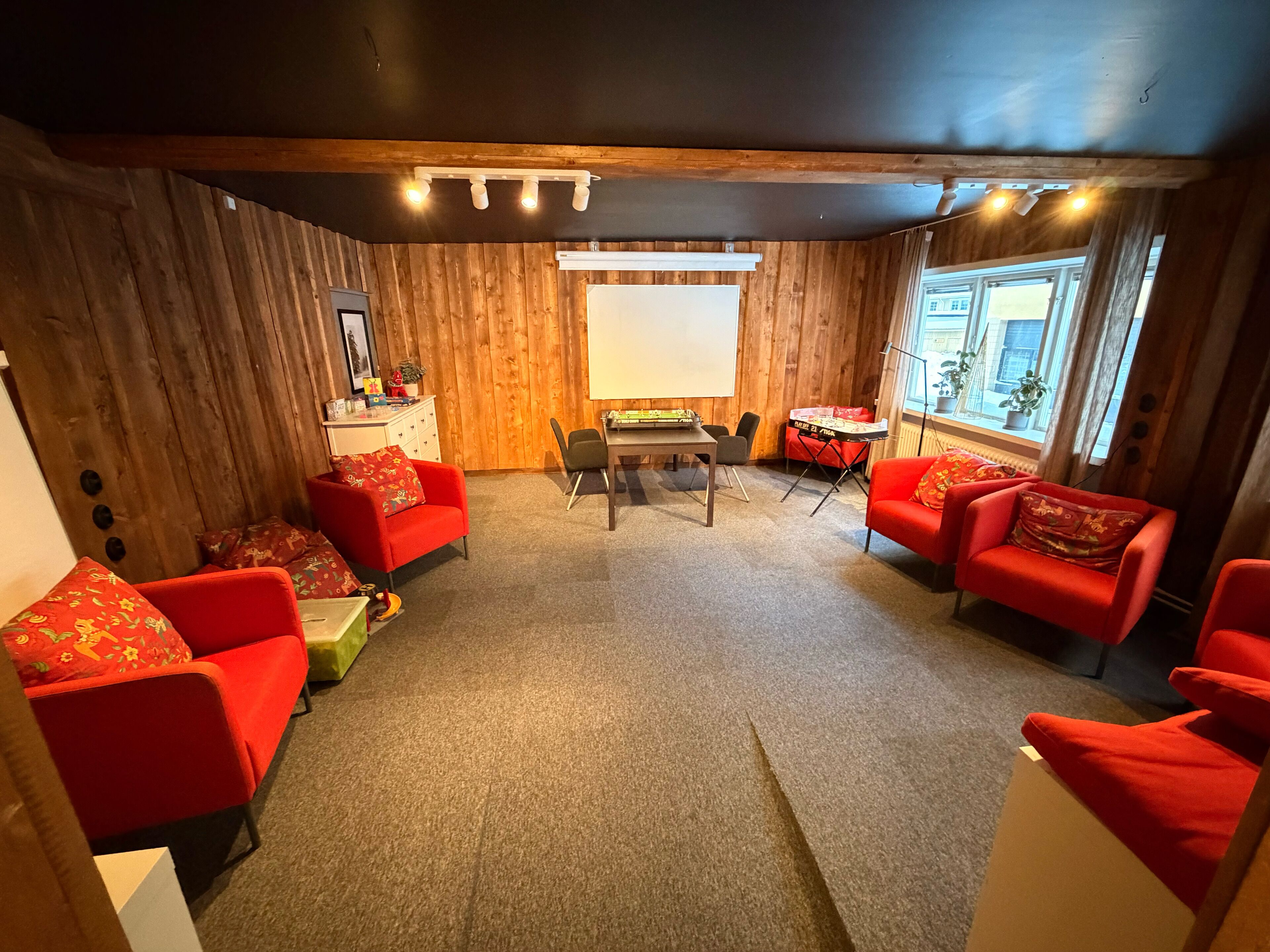Una habitación acogedora con paredes de madera, una mesa con sillas y sofás rojos.