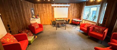 Una habitación acogedora con paredes de madera, una mesa con sillas y sofás rojos.