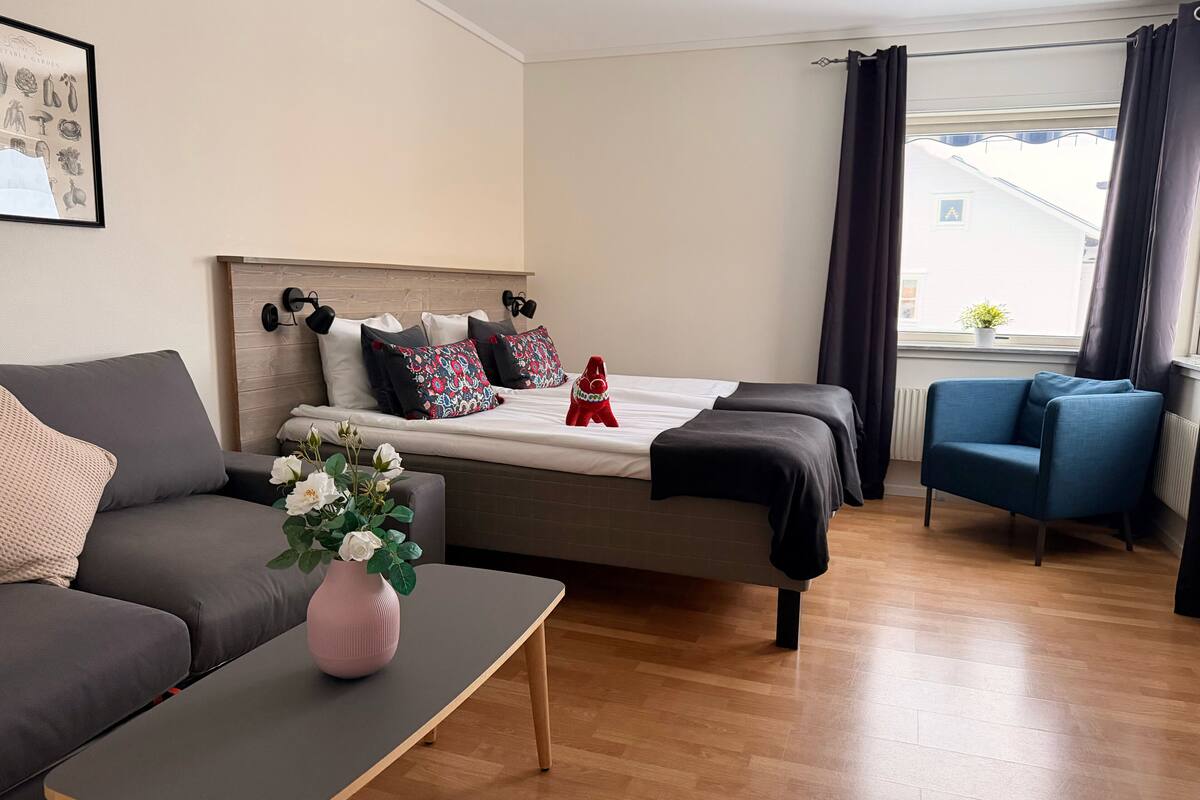 Una habitación de hotel moderna con una cama, un sofá, una mesita y una silla.