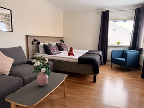 Quarto de hotel moderno com uma cama, um sofá, uma mesinha e uma cadeira.