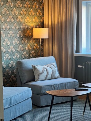 A room with a sofa, a small table, a lamp, and a radiator.
