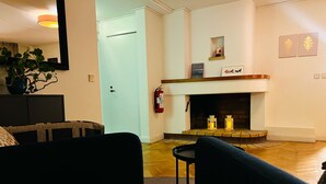 A living room with a fireplace, a sofa, a chair, and a small table. - Fridhemsgatan City Stay (Mora)