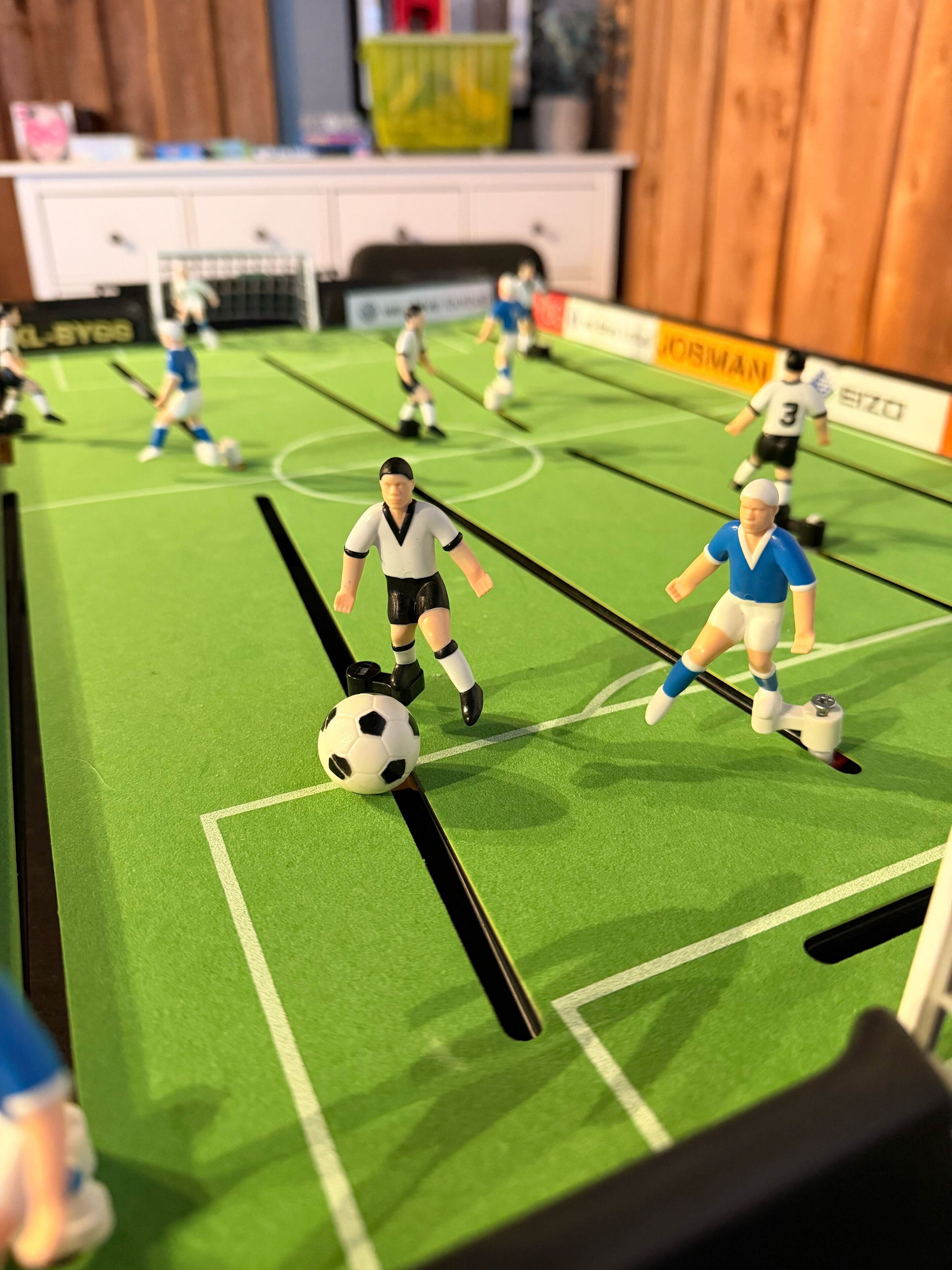 En liten fotbollsplan med spelare i full fart, ett mål och en resultattavla.