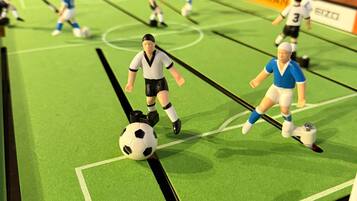 En liten fotbollsplan med spelare i full fart, ett mål och en resultattavla.