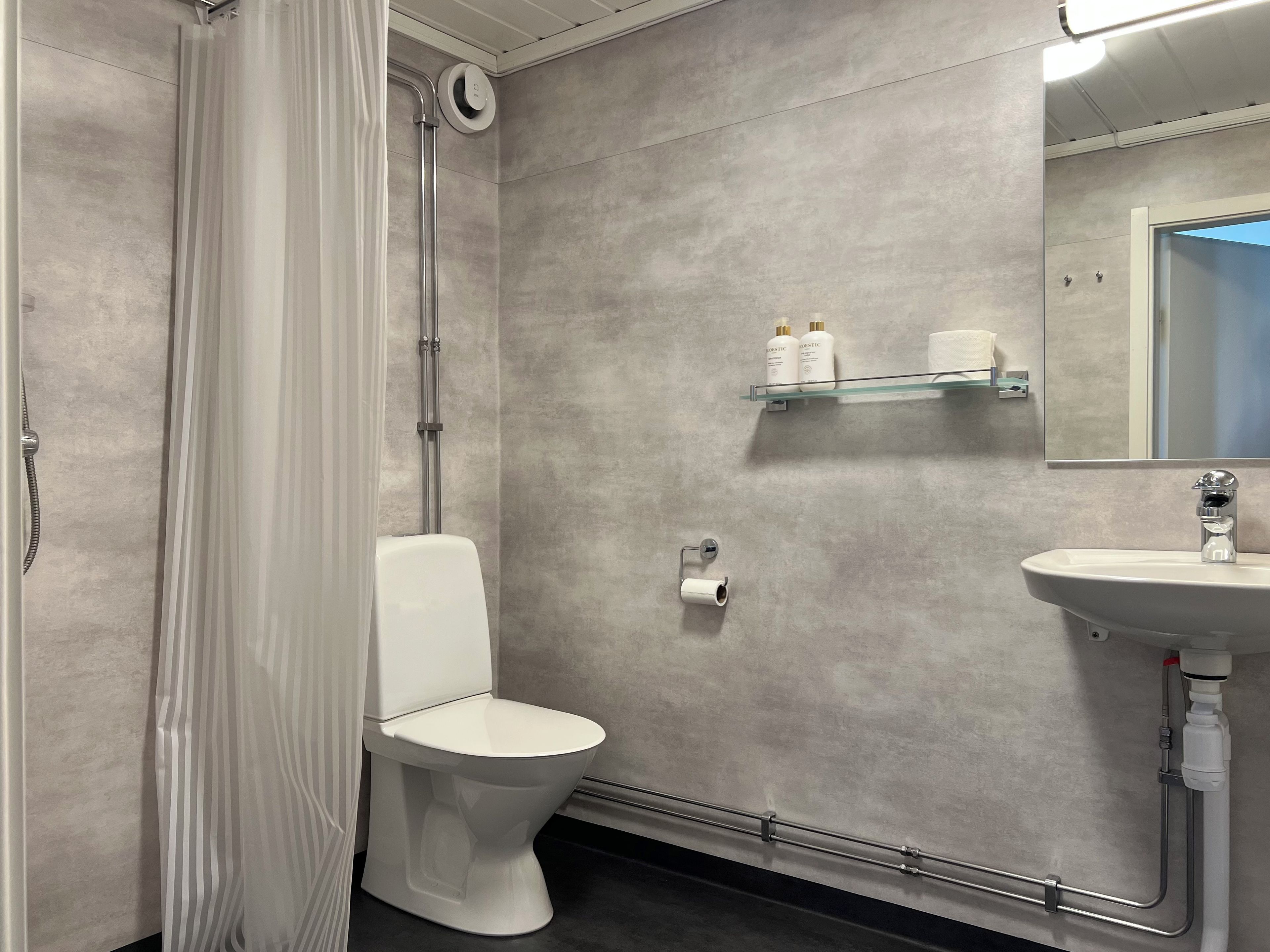 Une salle de bain moderne équipée de toilettes, d’une douche et d’un lavabo.