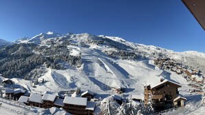 A snow-covered mountain with a ski resort, including wooden cabins and a lodge with a balcony.