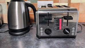 Cozinha com chaleira de aço inoxidável e torradeira no balcão.