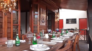 Un comedor con mesas de madera dispuestas para una comida, cristalería y adornos.