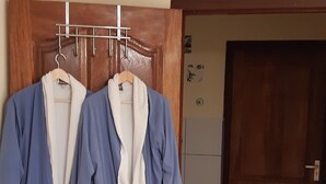 Una habitación con un armario de madera, suelo de baldosas y una puerta que da a otra estancia.