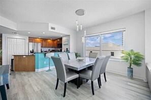 Una cocina moderna con una isla central, un comedor con mesa de mármol y un amplio ventanal con vistas.