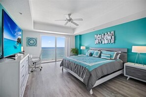 A bedroom with a bed, a desk, a chair, a ceiling fan, and a view of the ocean. - #702 Sanibel - Oceanfront Condo Panoramic Views (Daytona Beach Shores)