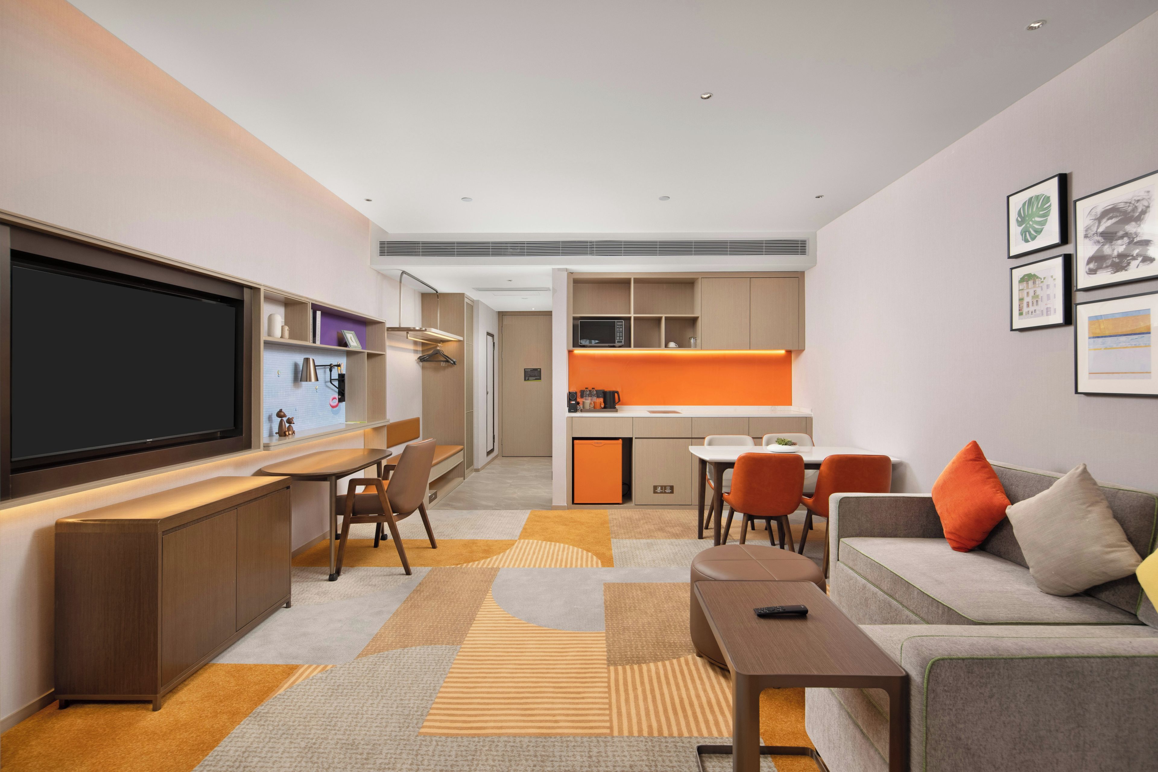 A modern living room with a flat-screen TV, a sofa, a coffee table, and a dining area with chairs.