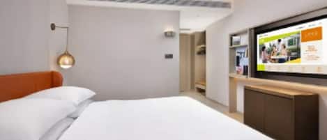 A modern hotel room with a large bed, a flat-screen TV, and a wooden cabinet.
