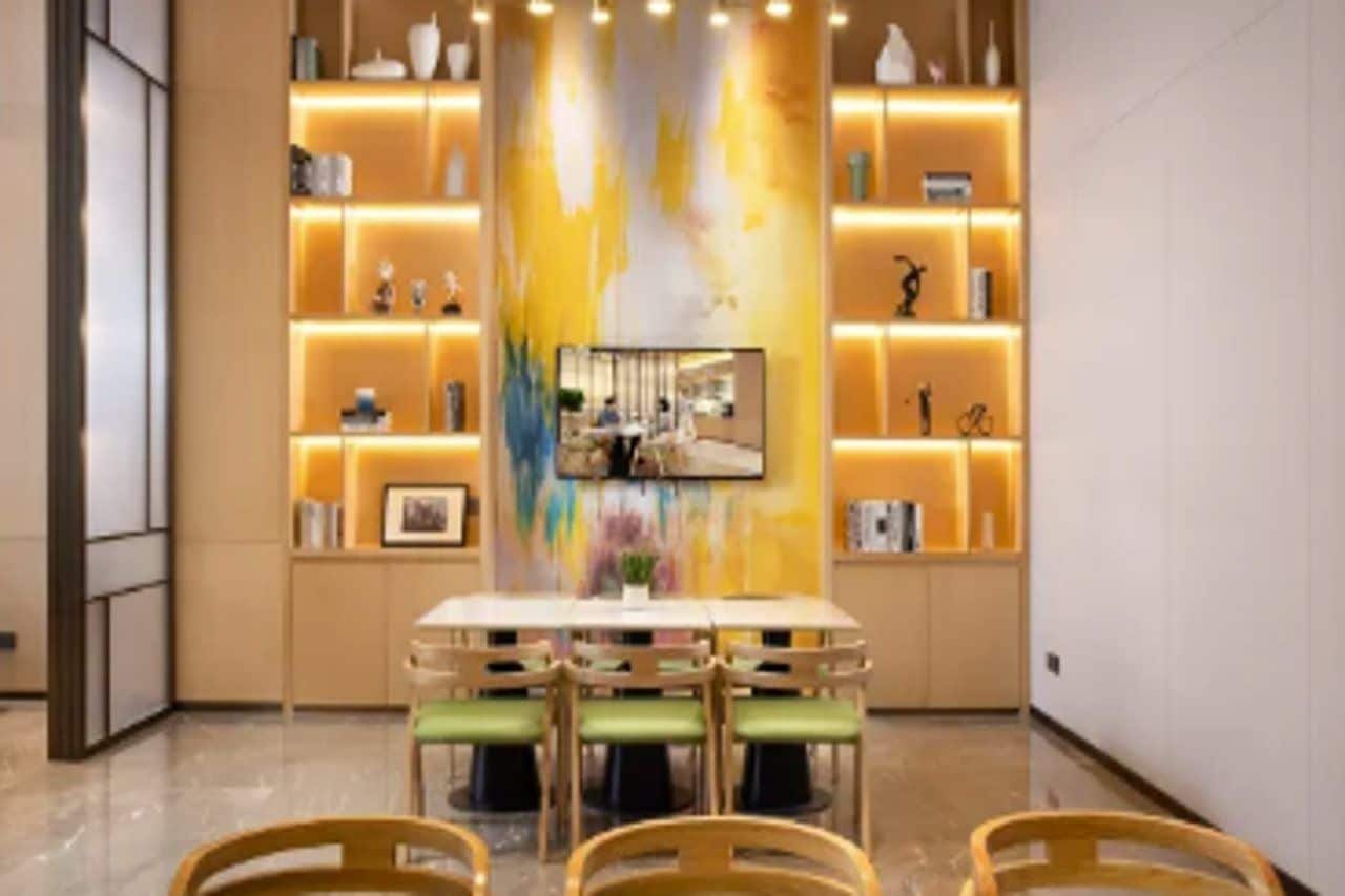 A dining area with a table and chairs, a wall-mounted TV, and shelves with decorative items.