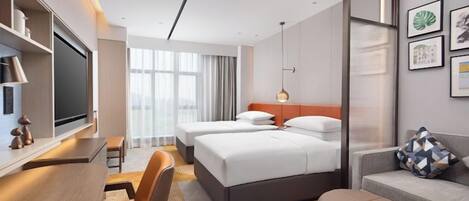 A hotel room with a bed, a desk, a chair, a sofa, and a TV.