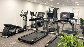 Un gimnasio con cintas de correr, elípticas y una bicicleta estática.
