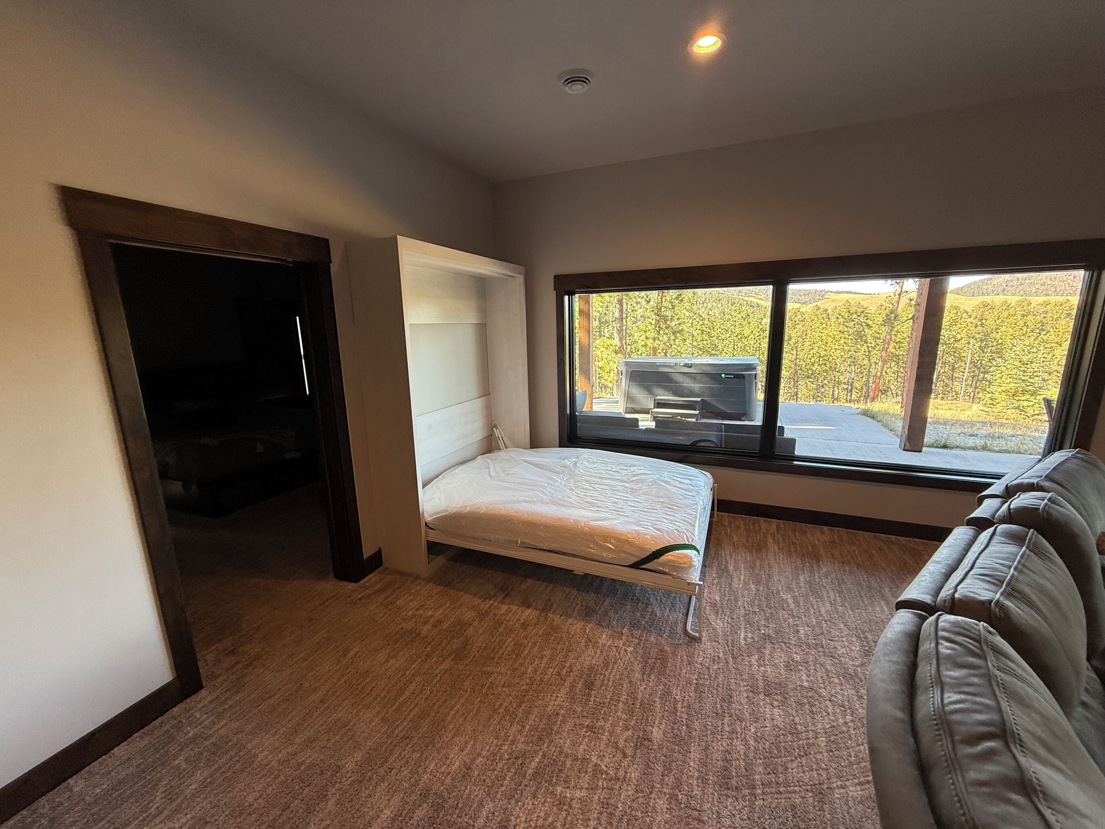 A bedroom with a bed, a window, and a view of a vehicle outside.