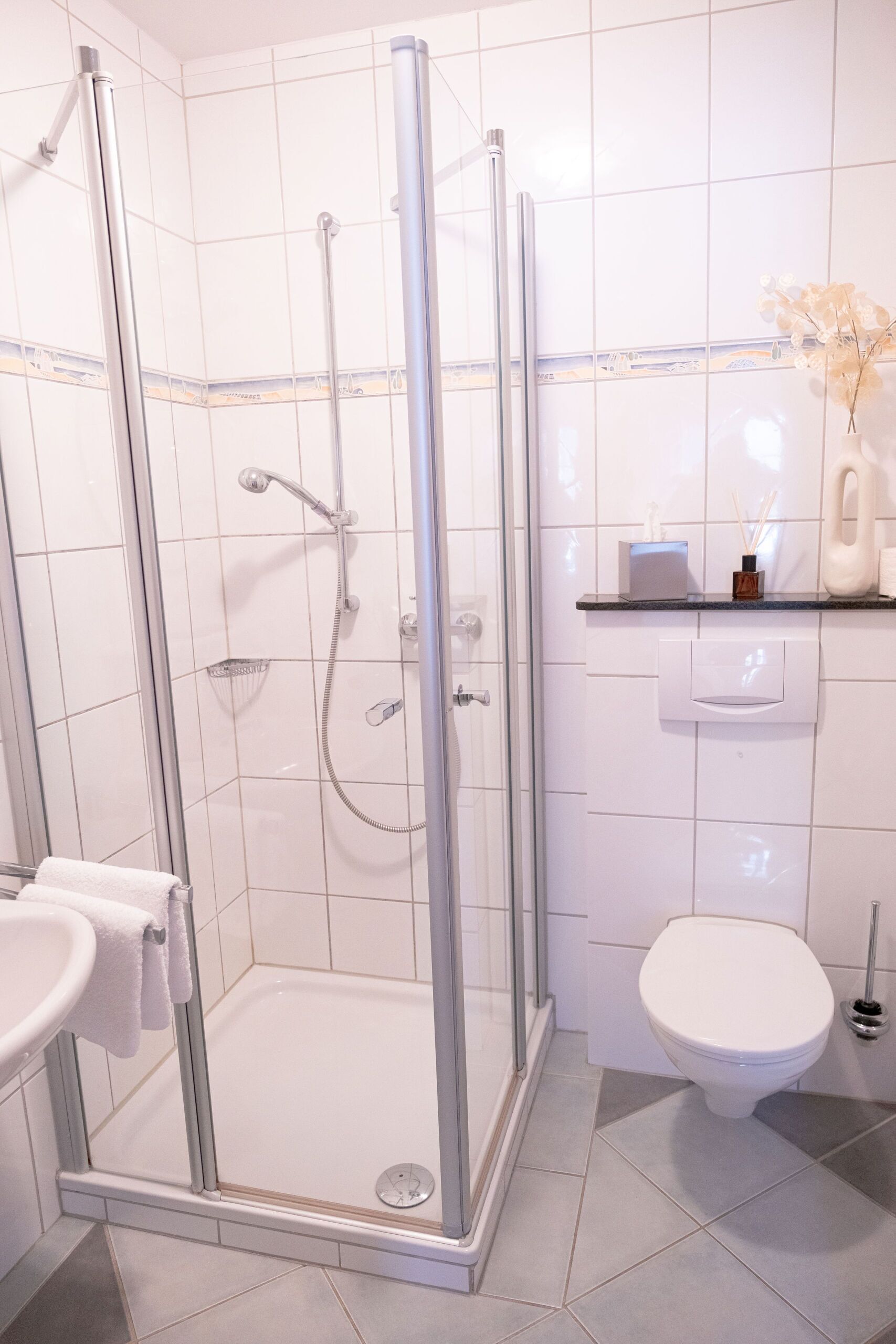 A modern bathroom with a glass-enclosed shower, a white toilet, and a sink with a towel.