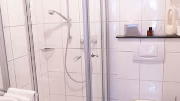 A modern bathroom with a glass-enclosed shower, a white toilet, and a sink with a towel.