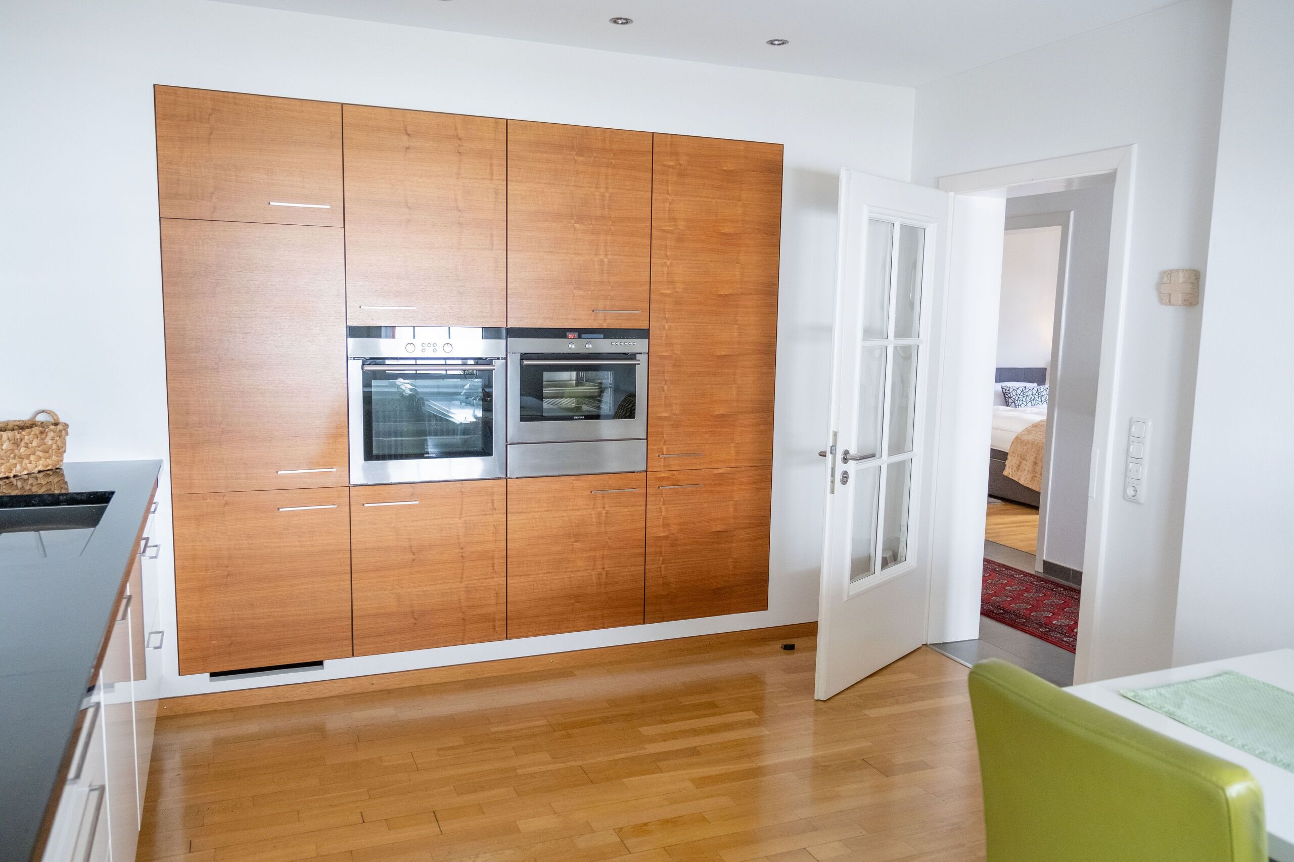 A modern kitchen with wooden cabinets, stainless steel appliances, and a wooden floor.