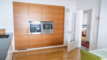 A modern kitchen with wooden cabinets, stainless steel appliances, and a wooden floor.
