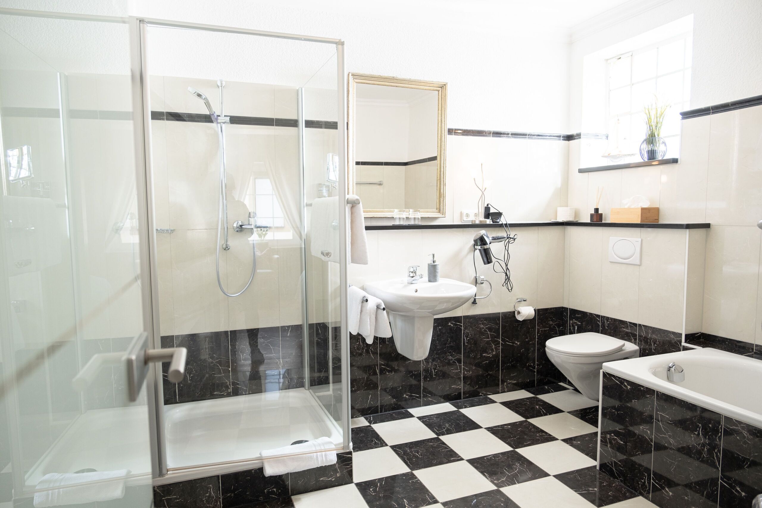Ein modernes Badezimmer mit einer Duschkabine, einem Waschbecken, einer Toilette und einer Badewanne.