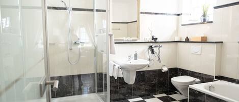 A modern bathroom with a glass-enclosed shower, a sink, a toilet, and a bathtub.