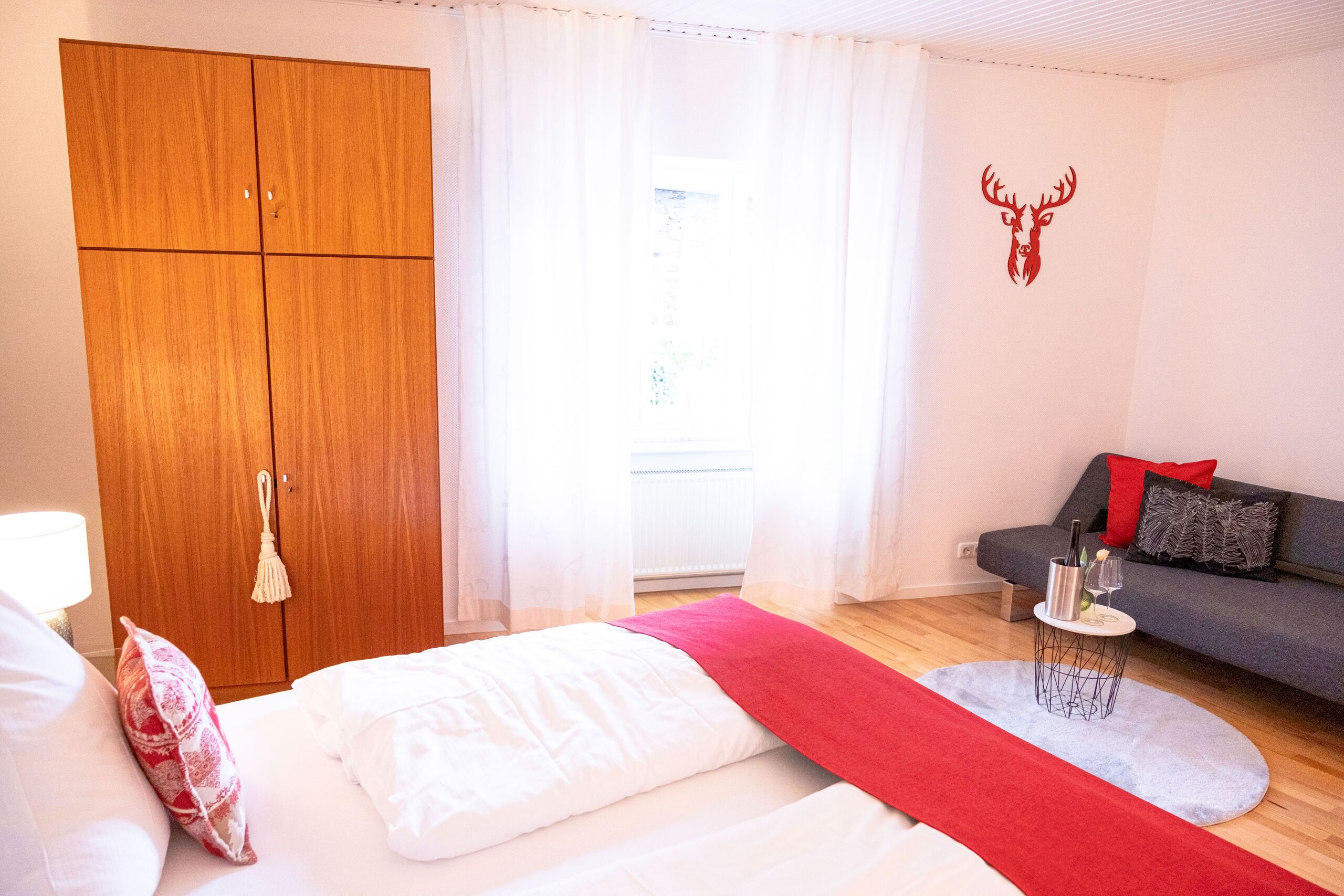 A bedroom with a bed, a wardrobe, a sofa, and a red runner.