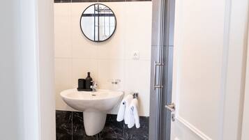 A bathroom with a checkered floor, a sink, a mirror, and a shower.