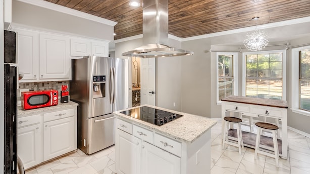 A modern kitchen with white cabinetry, stainless steel appliances, a wooden ceiling, and a large window. - Royal Meadows (Jackson)