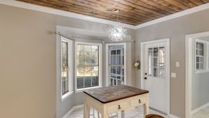 A room with a wooden ceiling, a white door, and a table with drawers. - Royal Meadows (Jackson)
