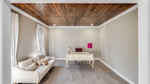 A room with a wooden ceiling, a white sofa, a white dresser, and a red lamp. - Royal Meadows (Jackson)