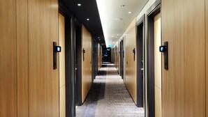 A hotel corridor with wooden walls, carpeted floors, and doors with digital displays. - ibis Surabaya Tidar (Surabaya)