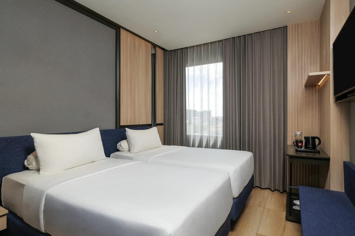 A hotel room with two beds, a TV, a coffee maker, and a view of the city.