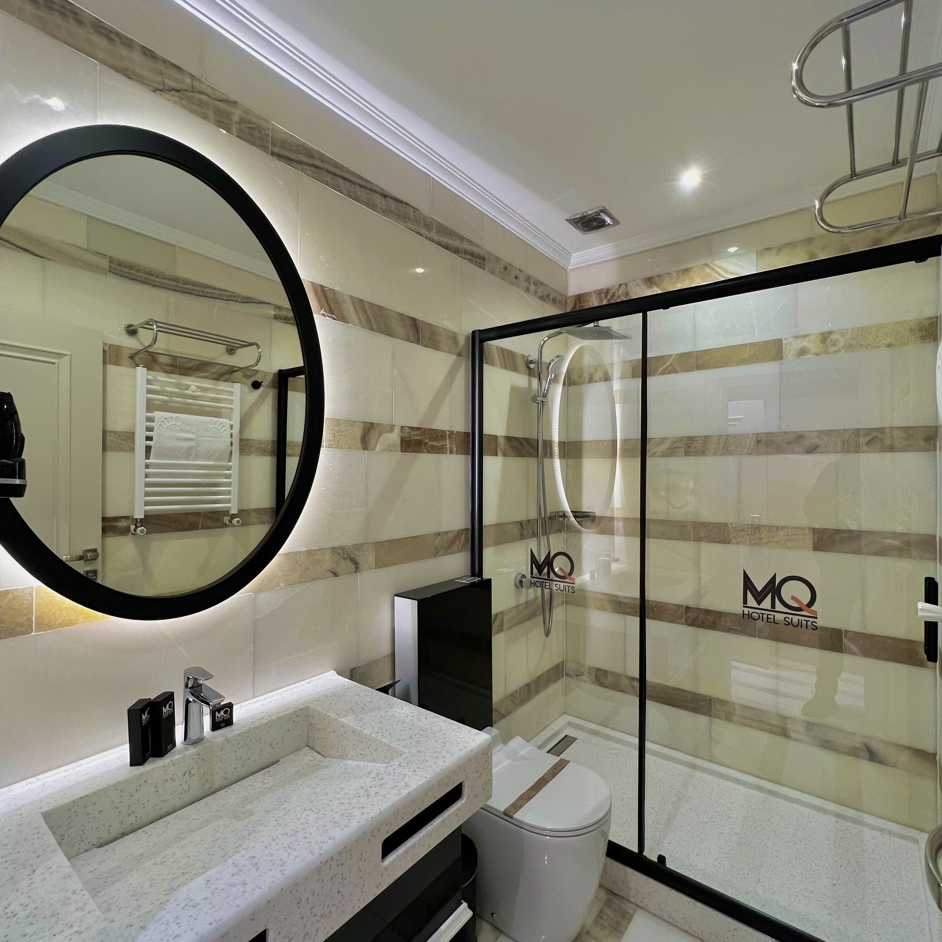 A modern bathroom with a large mirror, a sink, a toilet, and a glass-enclosed shower.