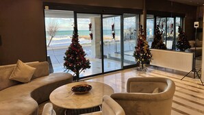 Recepció d'hotel moderna amb una finestra gran que ofereix vistes a la platja i amb els típics ornaments de Nadal.