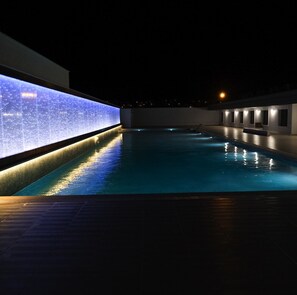 Una piscina al aire libre, sillones reclinables de piscina