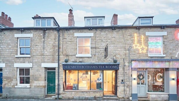 A stone building with a tea room named "Elizabeth Botham's Tea Rooms" and a shop with festive decorations. - Host & Stay | Sleepers @ No.8 (Pickering)