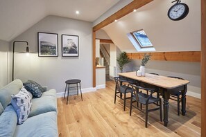 A cozy loft-style room with a dining area, a sofa, and a skylight. - Host & Stay | Sleepers @ No.8 (Pickering)