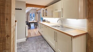 A modern kitchen with light-colored cabinets, a wooden countertop, and a large sink. - Host & Stay | Sleepers @ No.8 (Pickering)