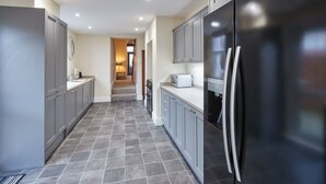 A modern kitchen with grey cabinets, a black refrigerator, and a microwave on the countertop.