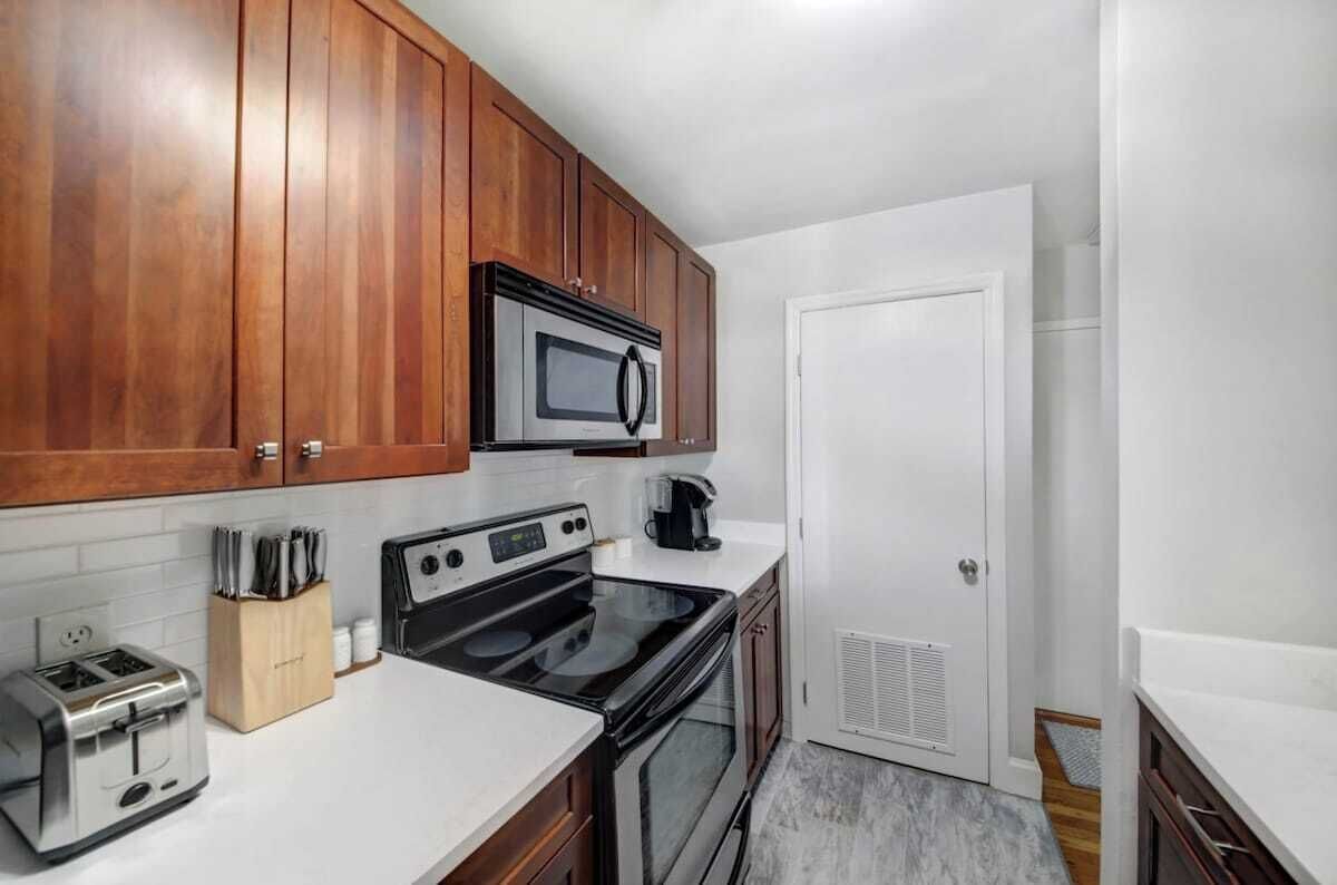 A compact kitchen with wooden cabinets, a microwave, a toaster, and a stove.