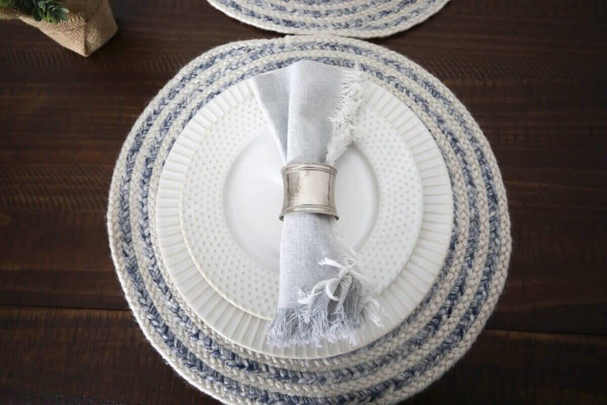 A round table with a white plate and a napkin holder.