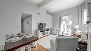 Un salon moderne comprenant une table à manger, un canapé et un téléviseur posé sur un meuble.