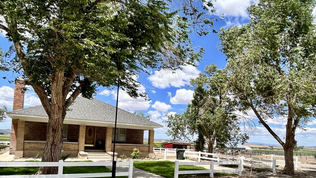 A rustic building with a brick exterior and a covered porch, surrounded by trees and a white fence. - The Spacious, Vintage House on the Ranch
 (Enoch)