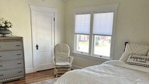 A bedroom with a bed, dresser, chair, and a window with blinds. - The Spacious, Vintage House on the Ranch
 (Enoch)