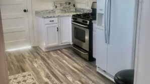 A kitchen with white cabinets, a stainless steel stove, a white refrigerator, and a wooden floor. - The Spacious, Vintage House on the Ranch
 (Enoch)