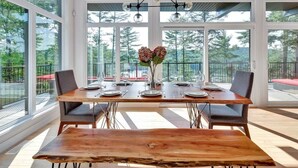 Un coin repas avec une grande table en bois, deux chaises et un vase rempli de fleurs.