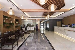 A hotel lobby with a reception desk, a long dining table, and a staircase. - Tonghuali Hotel (Lankao)