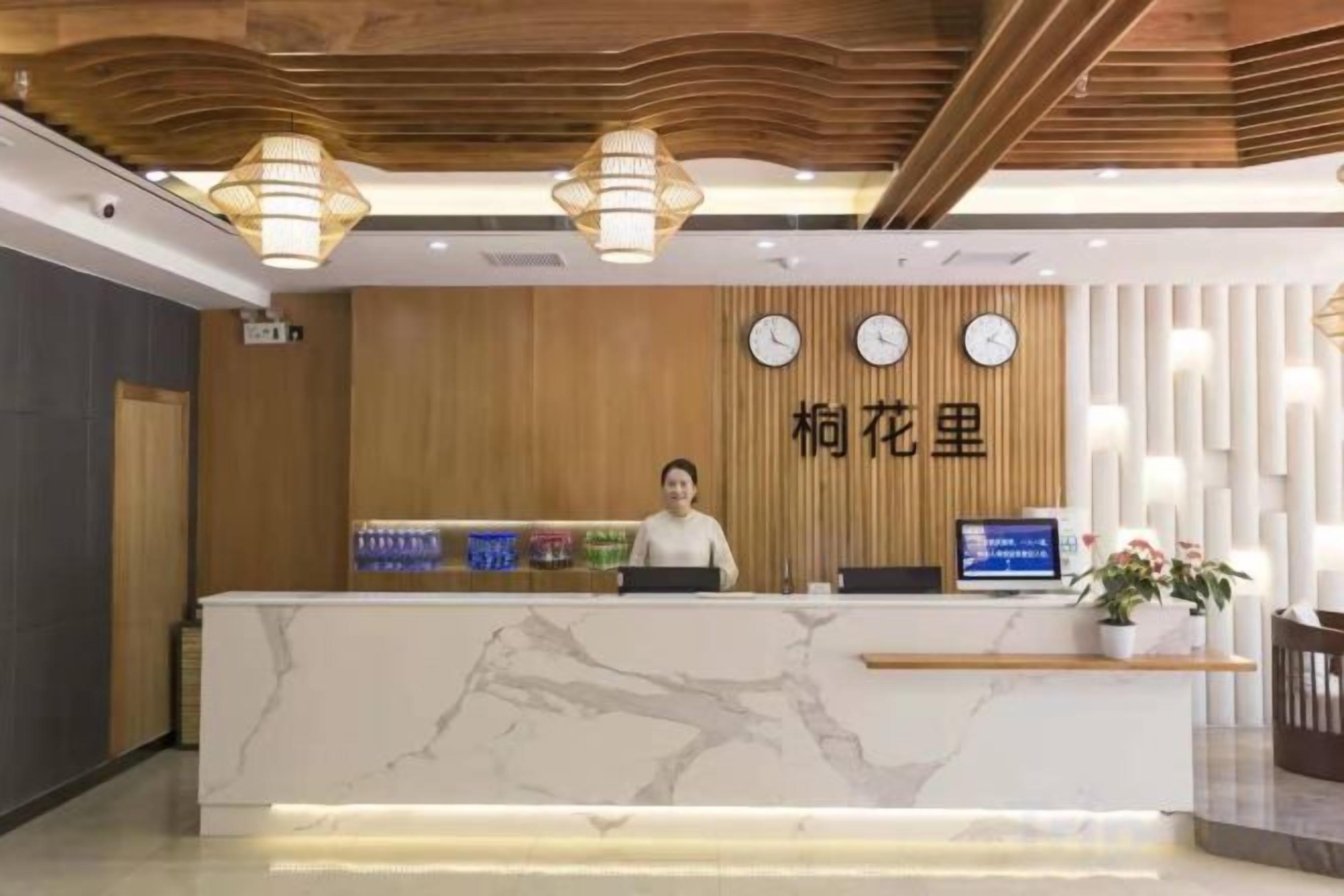 Una recepción de hotel con un panel de pared de madera, un reloj y una pantalla digital.